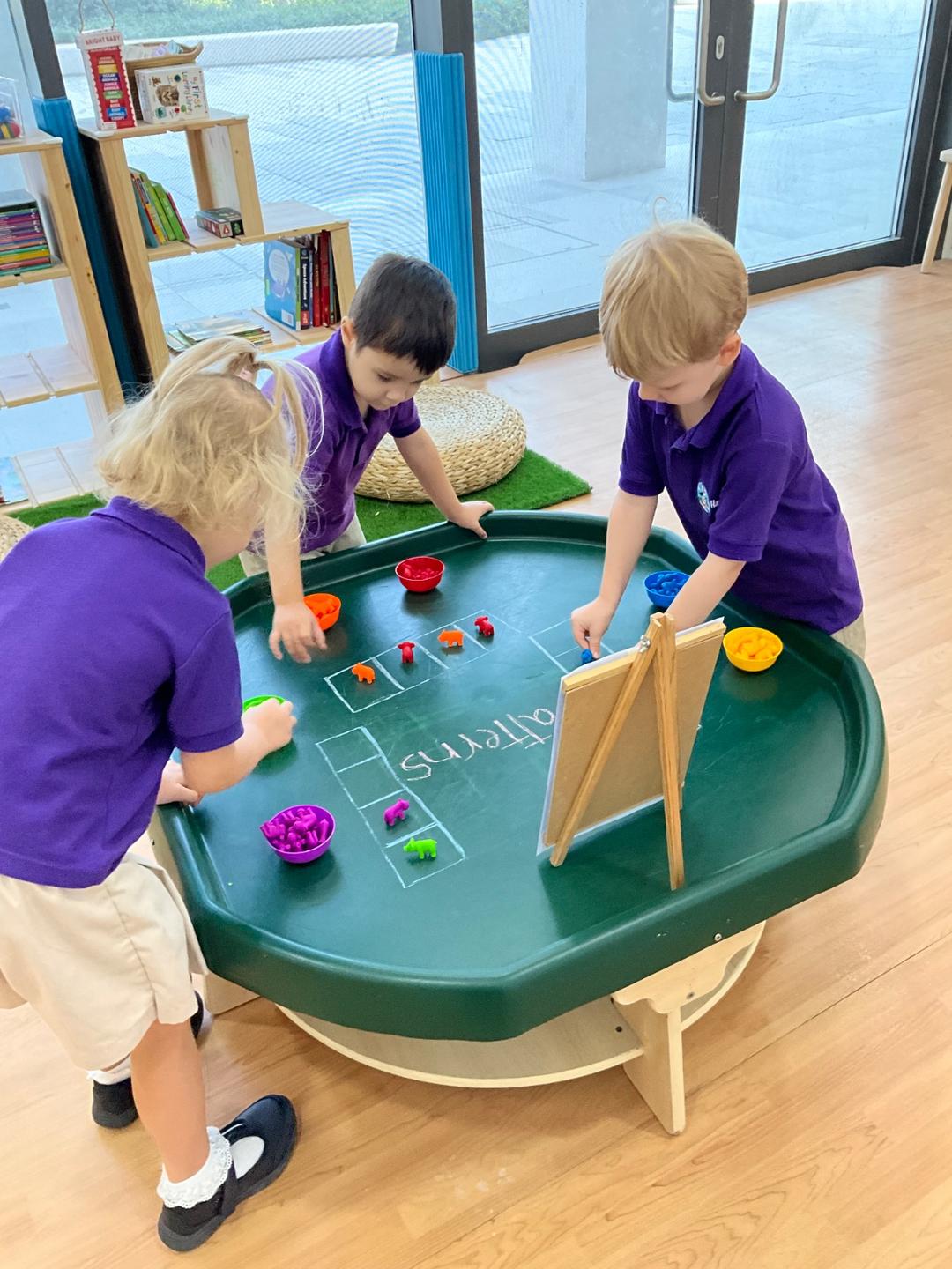 Children in nursery uniform sorting colourful counters into patterns at an activity tray