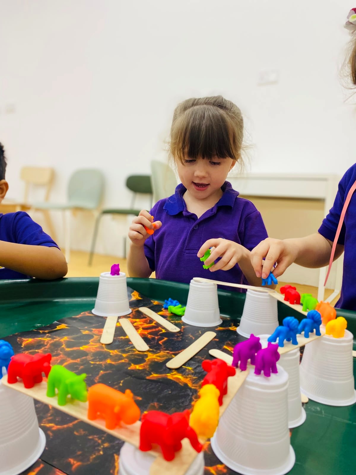Children building small bridges with cups and craft sticks for toy animals