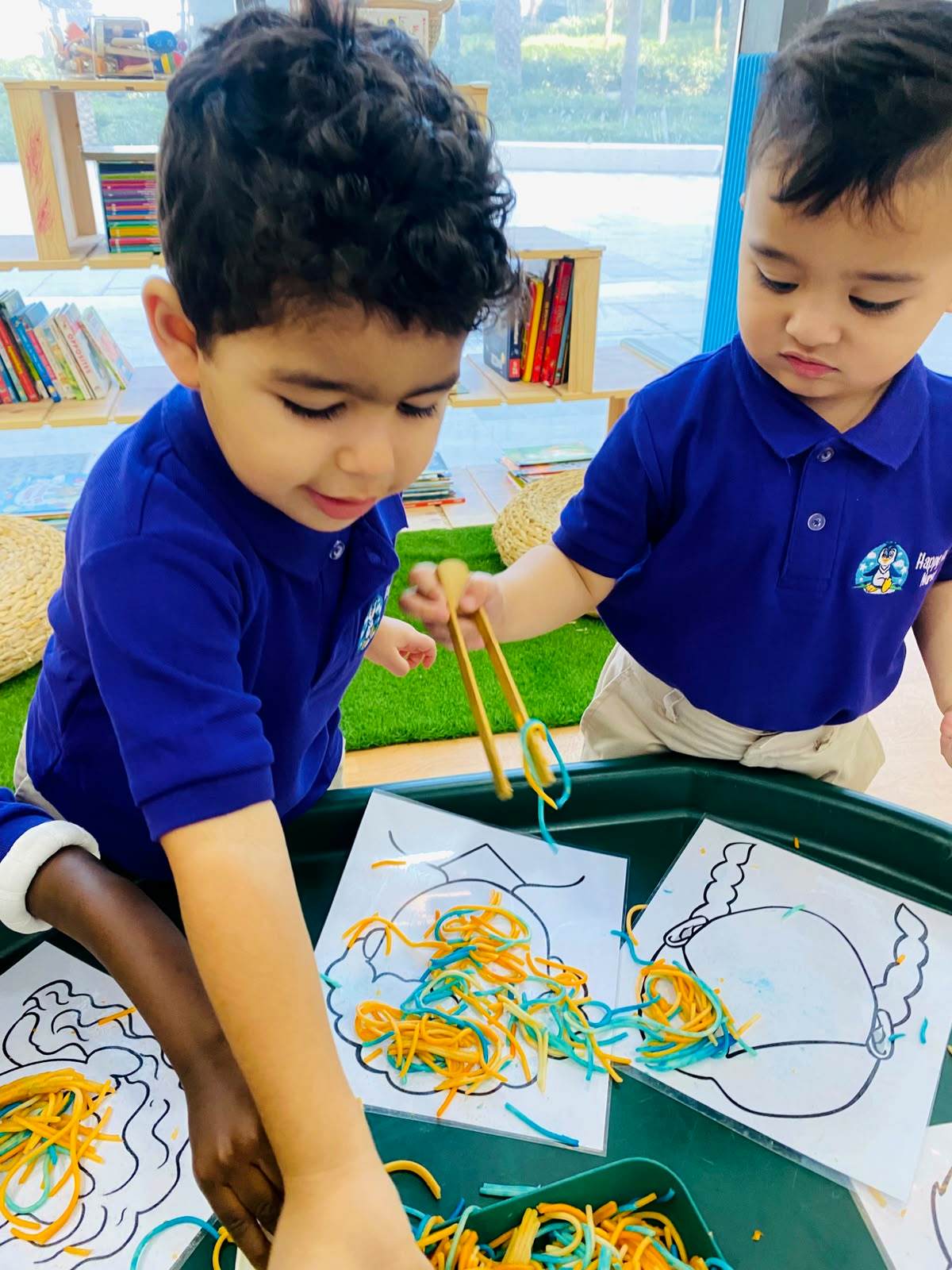 Children using tongs to explore colourful spaghetti during sensory play