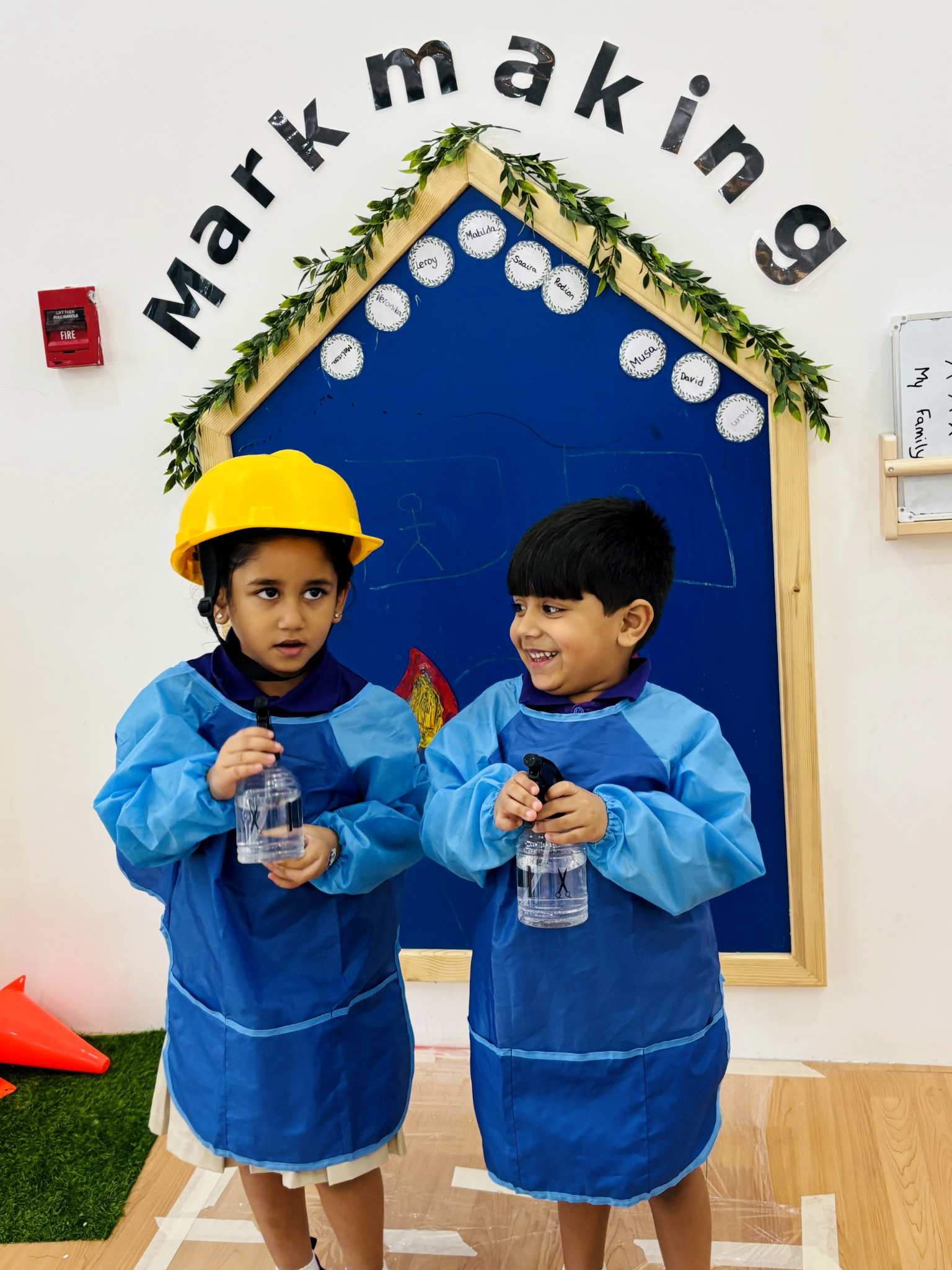 Children wearing aprons and using spray bottles during creative role play