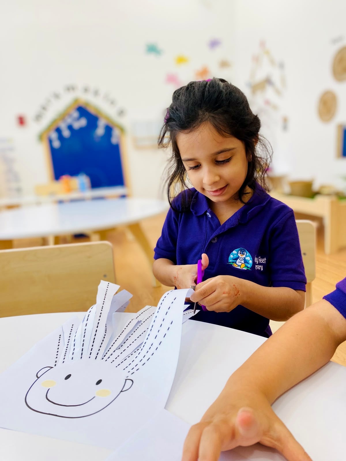 Child practising scissor skills by cutting along printed lines