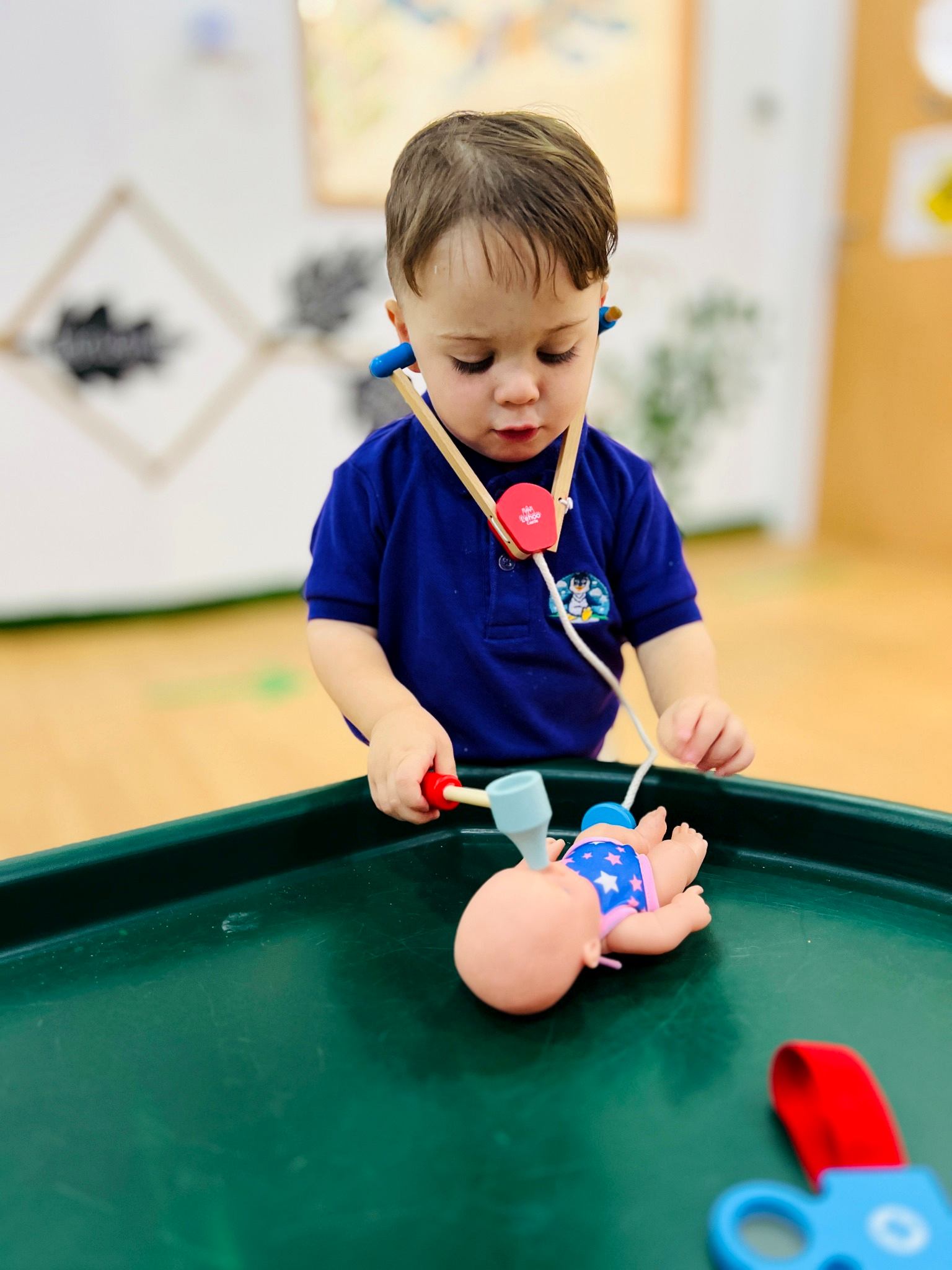Child using a toy stethoscope and medical tools to care for a doll