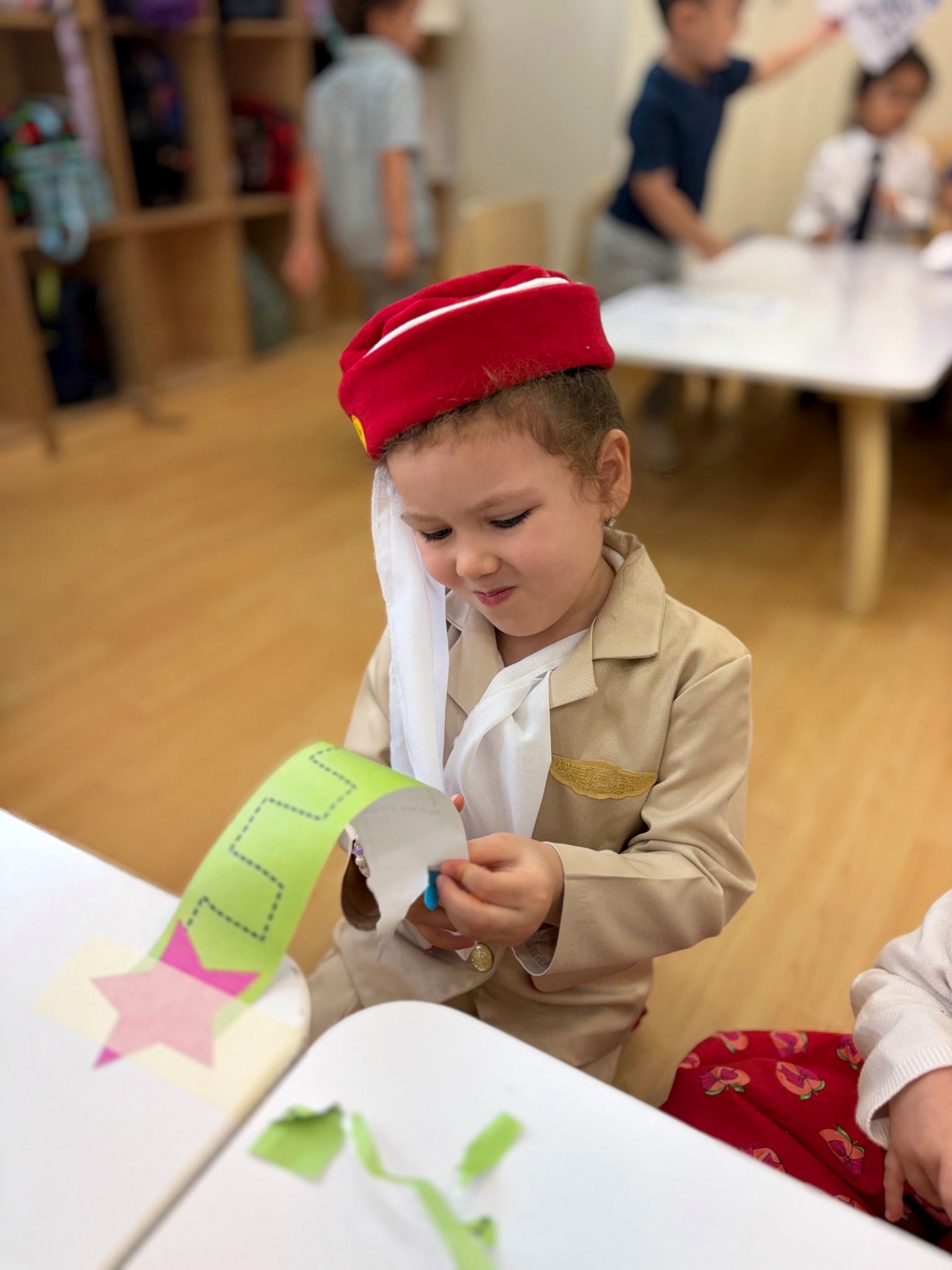 Child in a dress-like-a-parent costume working on a paper craft