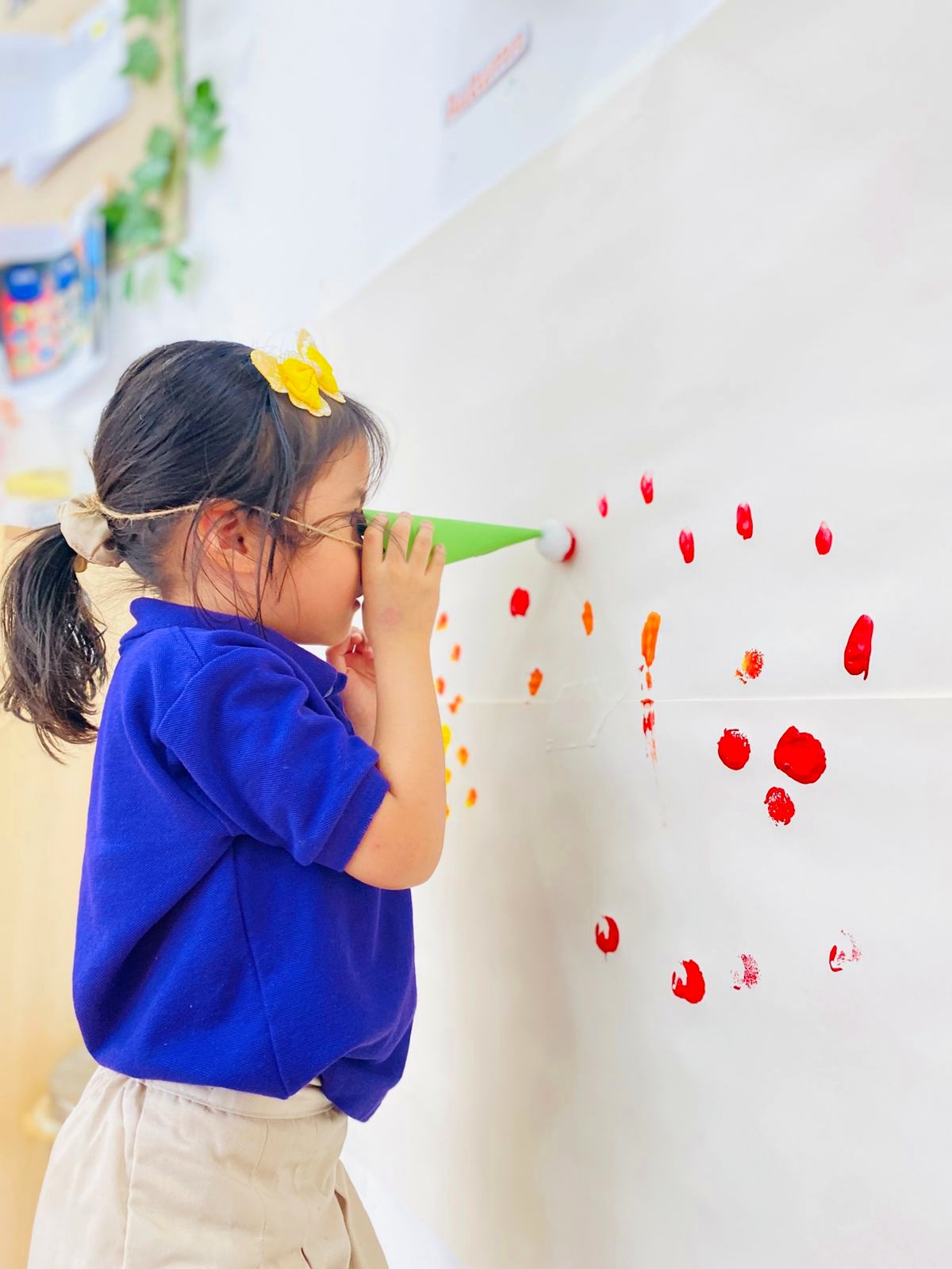 Child exploring colourful wall markings through a paper cone