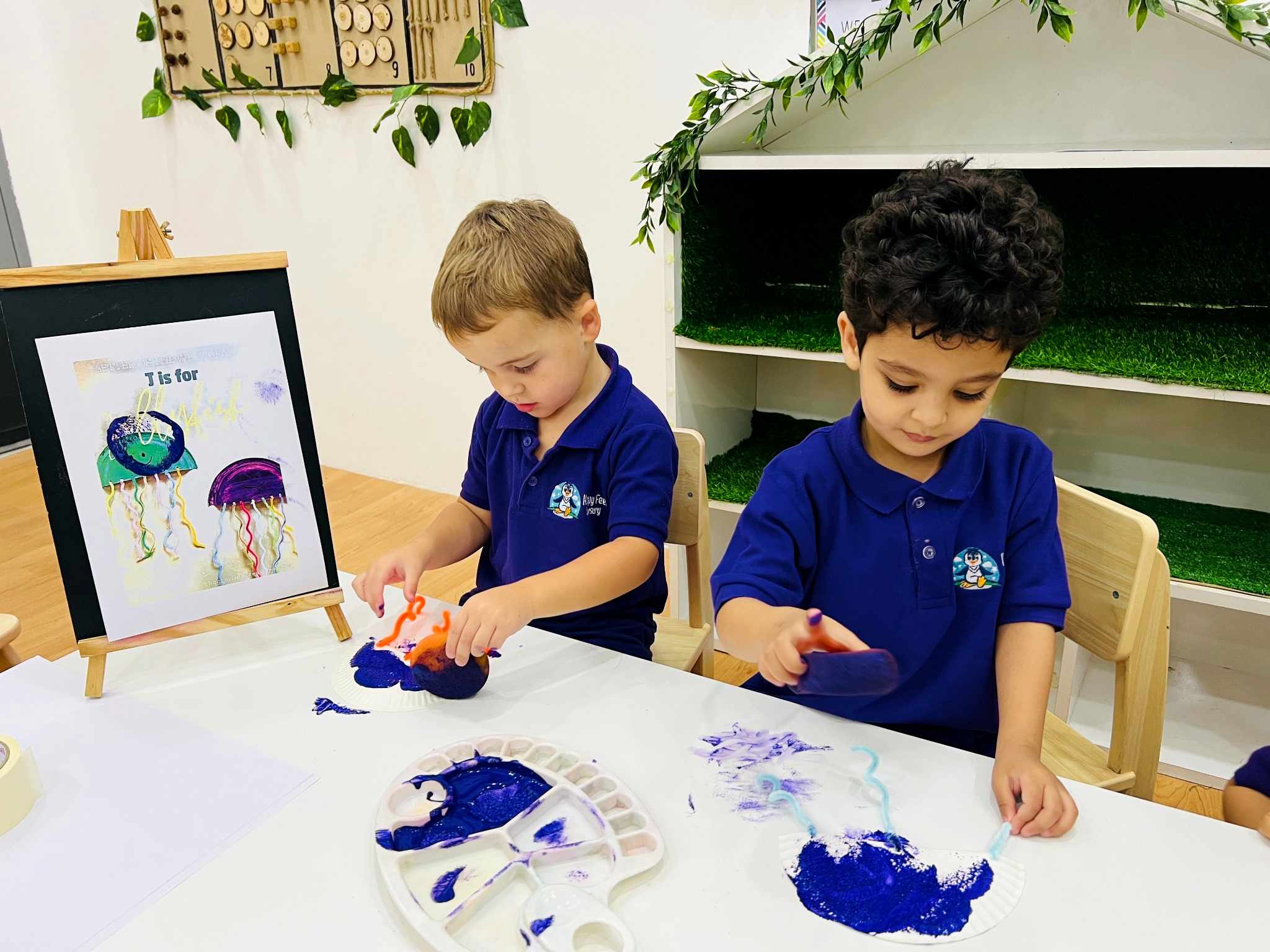 Children in nursery uniform making jellyfish prints with paint
