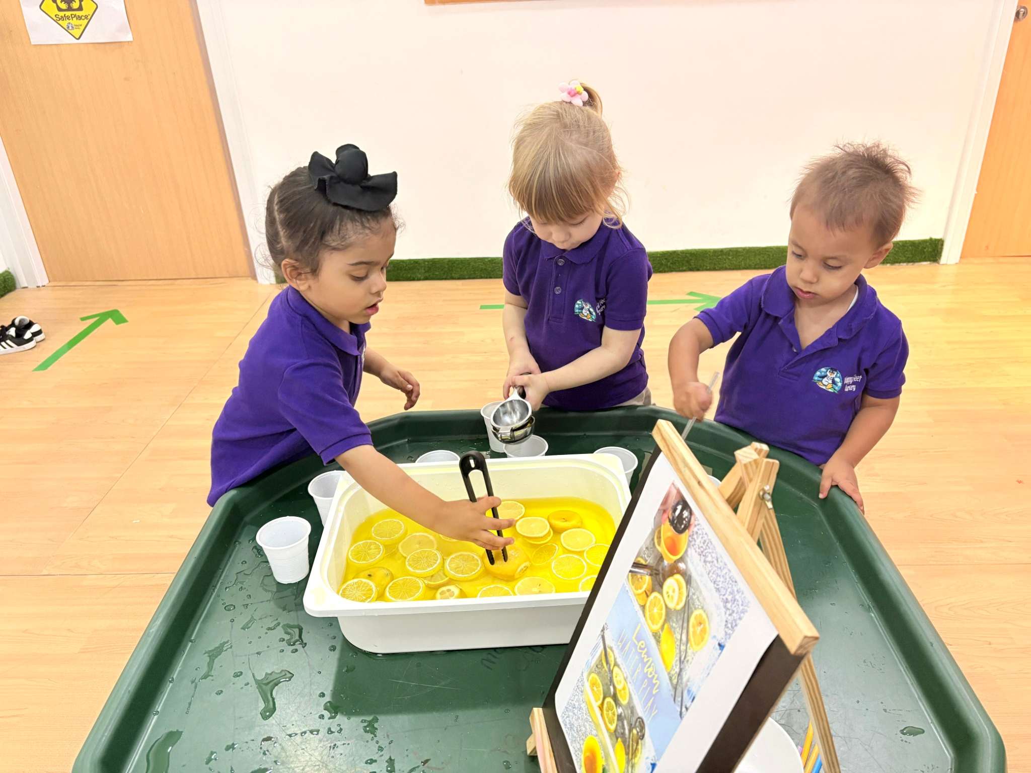Children scooping and pouring water with lemon slices during sensory play