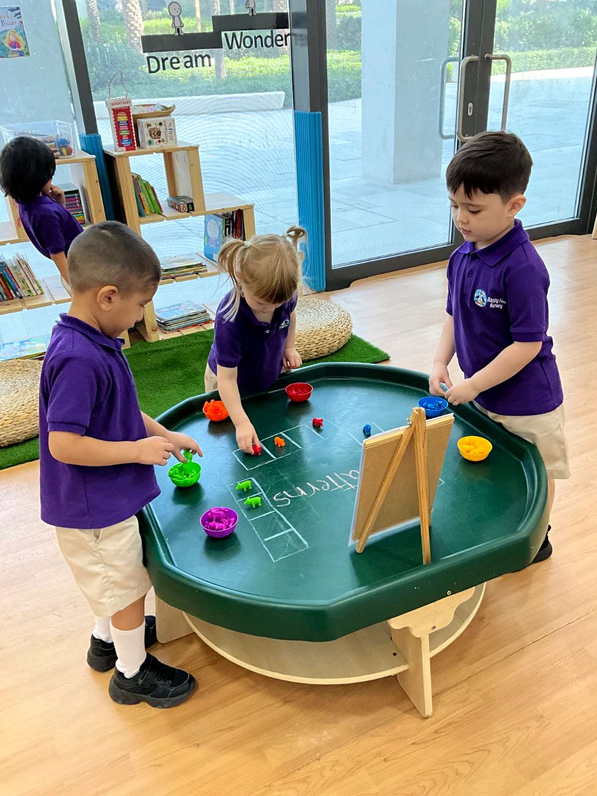 Children sorting colourful counters into matching bowls at a nursery activity tray