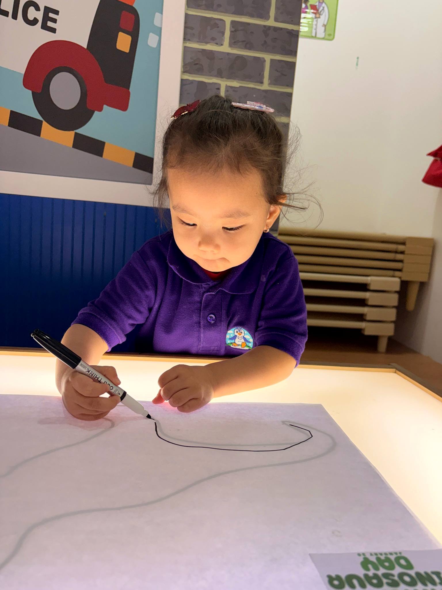 Child tracing an outline on a light table at Happy Feet Nursery